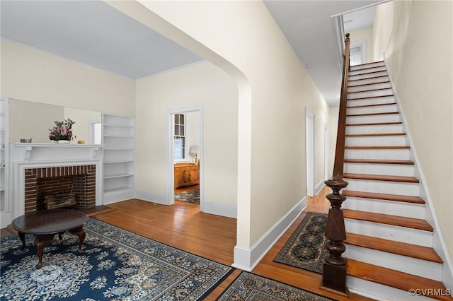 staircase featuring a brick fireplace and wood-type flooring