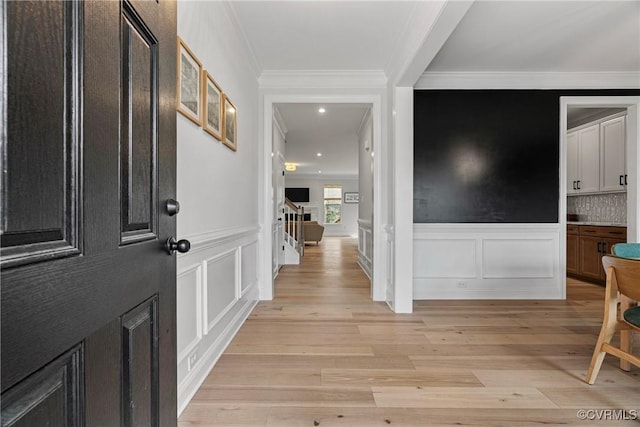 foyer entrance with ornamental molding and light wood-type flooring