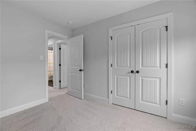 unfurnished bedroom with carpet, a closet, and baseboards