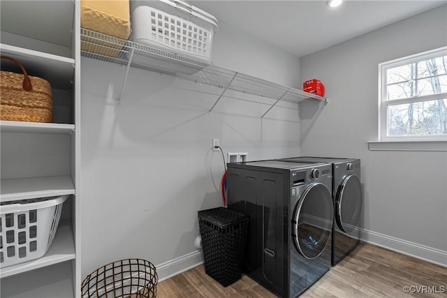 washroom featuring baseboards, laundry area, wood finished floors, and washer and dryer