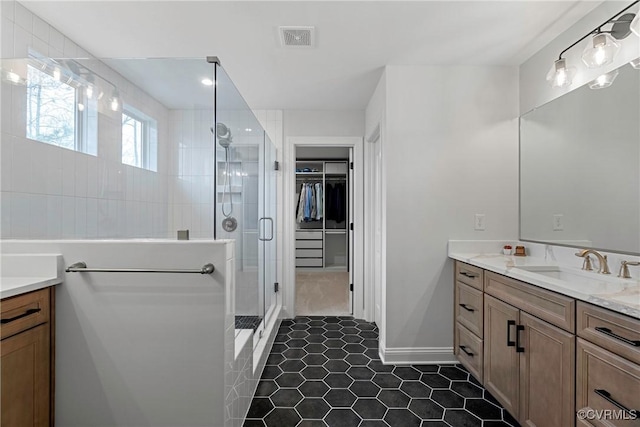 bathroom featuring visible vents, vanity, a shower stall, and a spacious closet