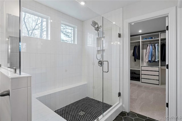 bathroom with a spacious closet and a shower stall