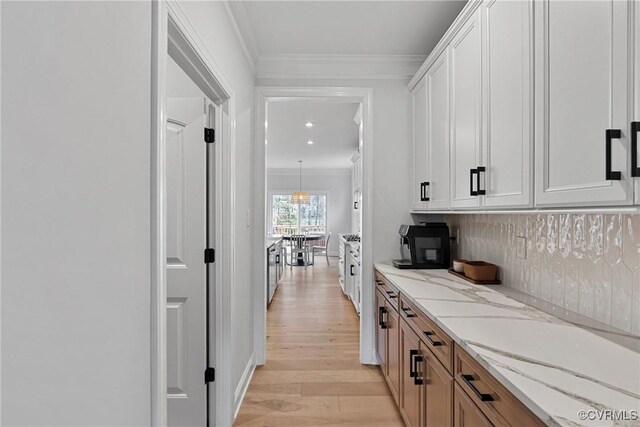 bar with light wood-style flooring, ornamental molding, and backsplash