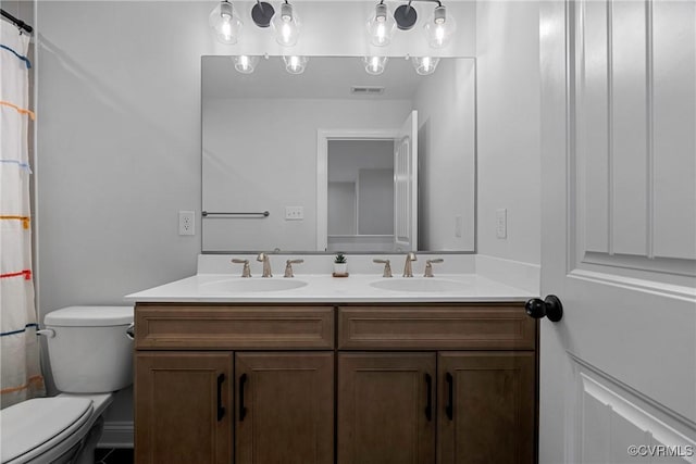 bathroom with visible vents, a sink, toilet, and double vanity