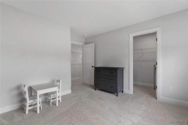 bedroom featuring a spacious closet, a closet, carpet flooring, and baseboards