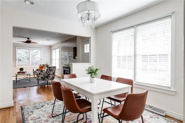 dining area with ceiling fan with notable chandelier and light hardwood / wood-style flooring