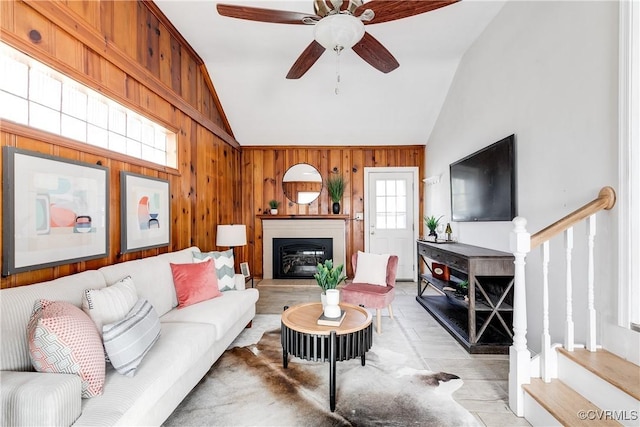 living room with vaulted ceiling, ceiling fan, and wood walls