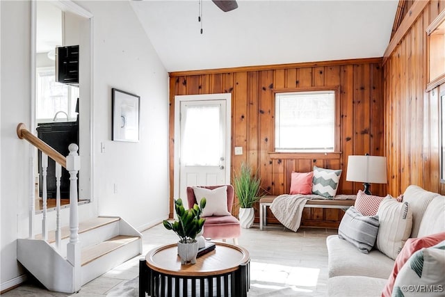 living room featuring vaulted ceiling, ceiling fan, and wood walls