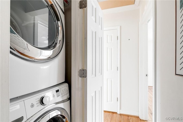 clothes washing area with stacked washer / drying machine and light hardwood / wood-style flooring