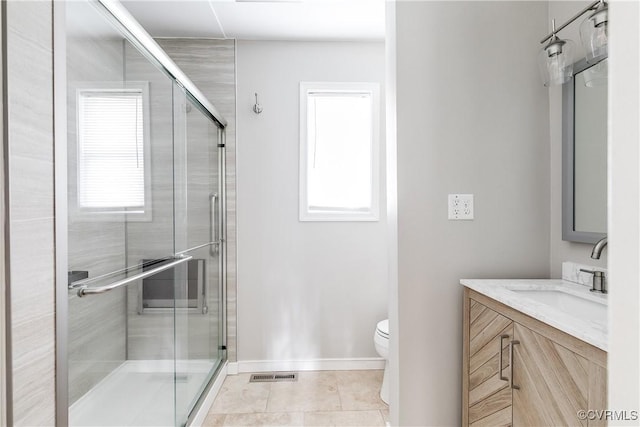 bathroom with a shower with door, vanity, tile patterned floors, and toilet