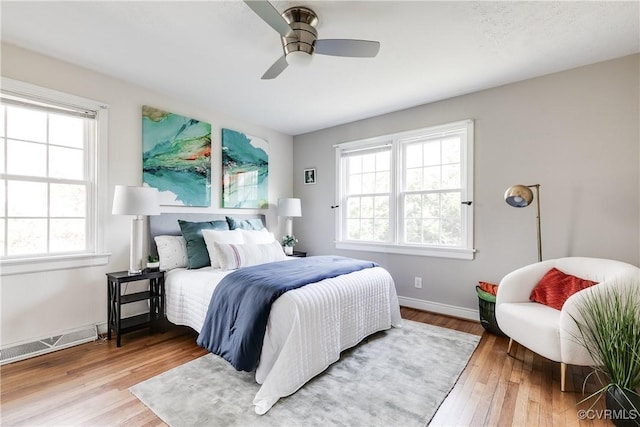 bedroom with hardwood / wood-style flooring, ceiling fan, and multiple windows