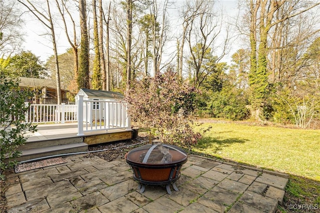 view of patio with a wooden deck, a shed, and a fire pit