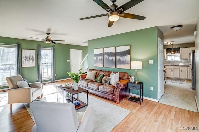 living room featuring ceiling fan, sink, and light hardwood / wood-style floors