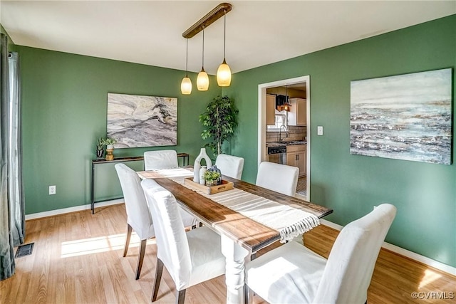 dining space with sink and light hardwood / wood-style flooring