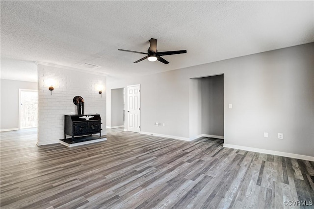 unfurnished living room with hardwood / wood-style flooring, a textured ceiling, ceiling fan, and a wood stove