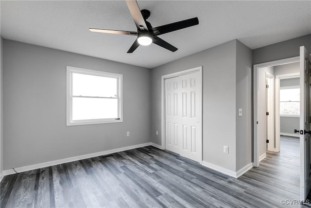 unfurnished bedroom featuring ceiling fan, dark wood-type flooring, a textured ceiling, and a closet