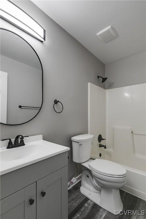 full bathroom featuring wood-type flooring, shower / bathing tub combination, vanity, and toilet