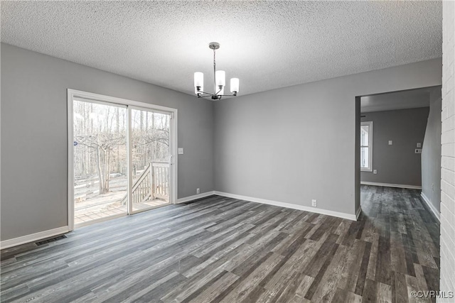 unfurnished dining area with dark wood-type flooring, a chandelier, and a textured ceiling