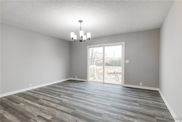 unfurnished room with dark wood-type flooring, a textured ceiling, and a notable chandelier