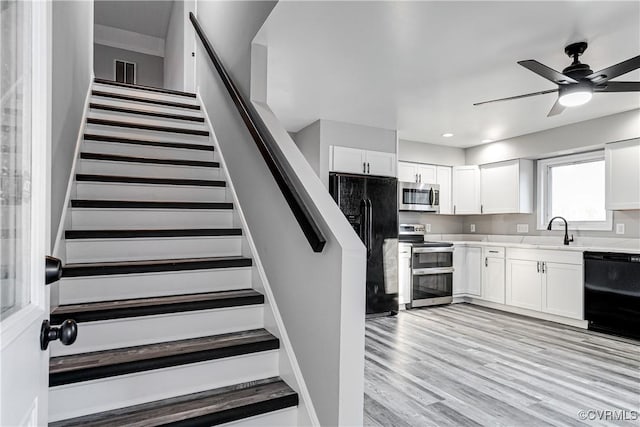 staircase featuring sink, hardwood / wood-style floors, and ceiling fan