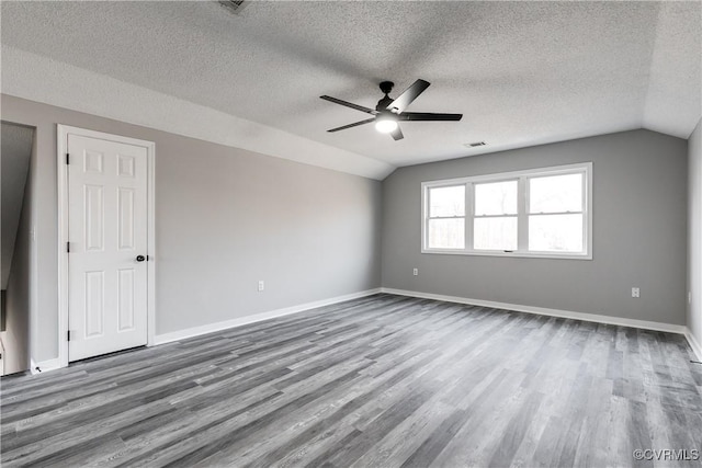 unfurnished room with hardwood / wood-style flooring, ceiling fan, vaulted ceiling, and a textured ceiling