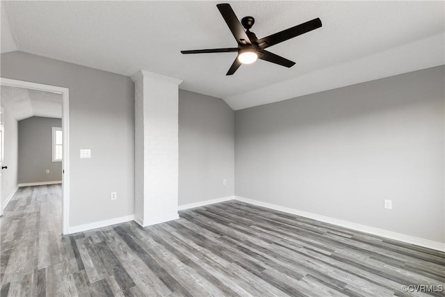 empty room with ceiling fan, vaulted ceiling, light hardwood / wood-style flooring, and a textured ceiling