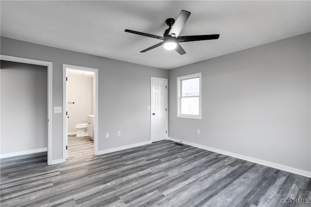 unfurnished bedroom featuring dark wood-type flooring, ceiling fan, ensuite bathroom, and a textured ceiling