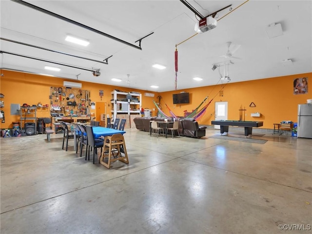 garage with stainless steel refrigerator, a garage door opener, a wall mounted AC, and a workshop area