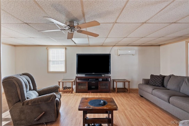 living room with a drop ceiling, wood-type flooring, an AC wall unit, and ceiling fan