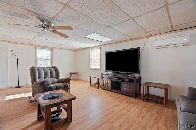 living room with ceiling fan, a paneled ceiling, a wall mounted AC, and light wood-type flooring