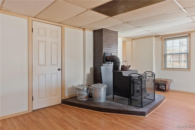 bar featuring wood-type flooring, a wood stove, and a drop ceiling