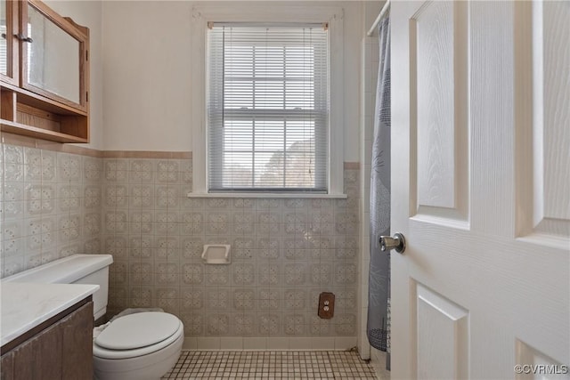 bathroom with vanity, tile patterned floors, tile walls, and toilet