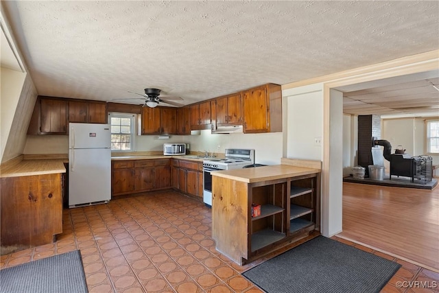 kitchen with white refrigerator, ceiling fan, a healthy amount of sunlight, and range with electric cooktop