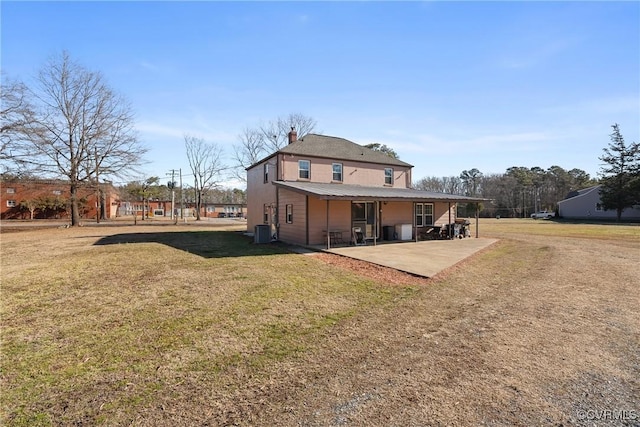 rear view of property with cooling unit, a patio area, and a lawn