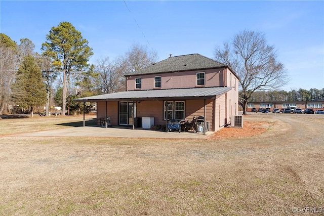 rear view of house featuring cooling unit, a lawn, and a patio