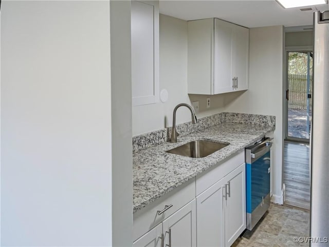 kitchen with light stone counters, sink, stainless steel dishwasher, and white cabinets