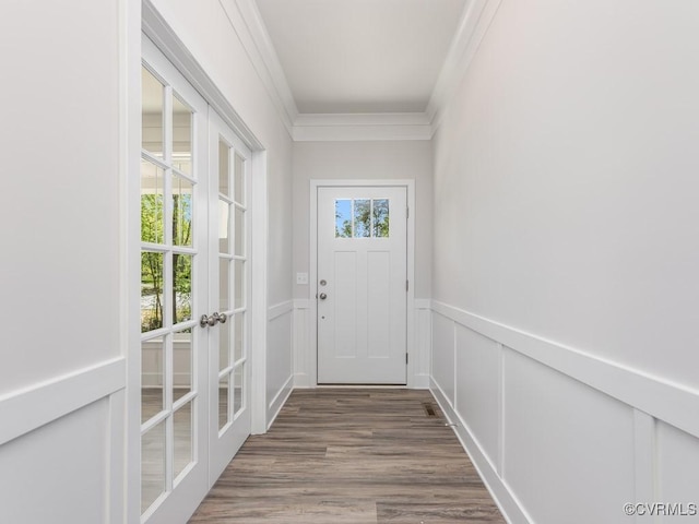 entryway featuring a decorative wall, a wainscoted wall, crown molding, and wood finished floors