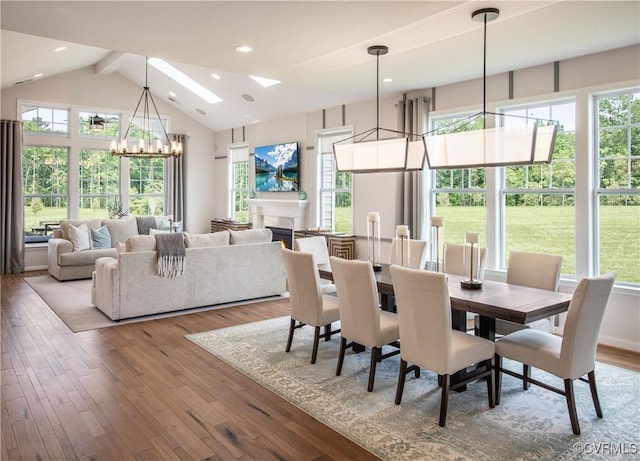 dining space with an inviting chandelier, light hardwood / wood-style flooring, vaulted ceiling with skylight, and a healthy amount of sunlight