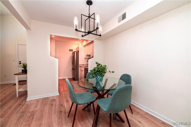 dining space with an inviting chandelier and light hardwood / wood-style flooring