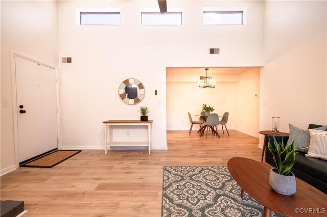 entryway featuring a towering ceiling, light hardwood / wood-style floors, and a chandelier