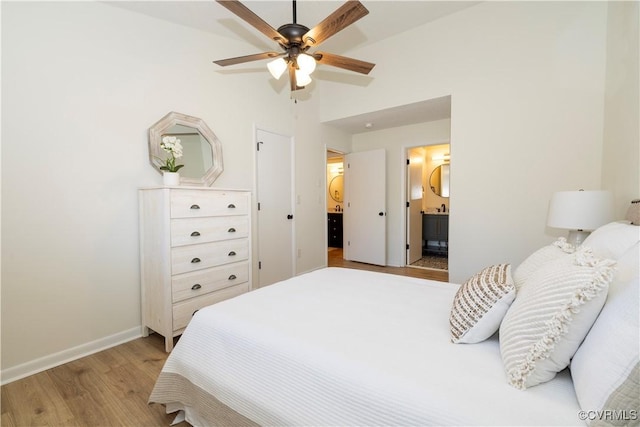 bedroom featuring ceiling fan, ensuite bath, lofted ceiling, and light hardwood / wood-style floors