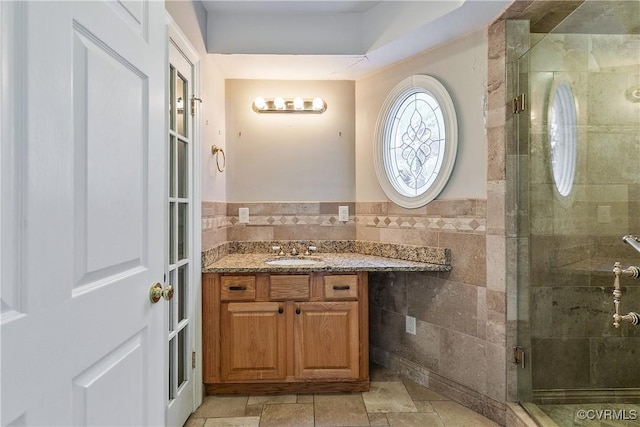 bathroom with vanity, a shower with shower door, and tile walls