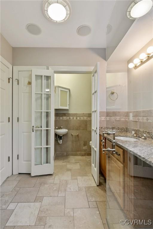 bathroom with tile walls, sink, and an inviting chandelier