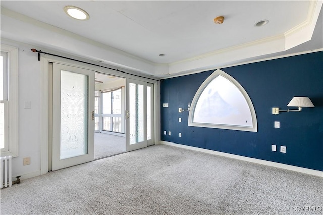 carpeted spare room with crown molding, radiator, and french doors