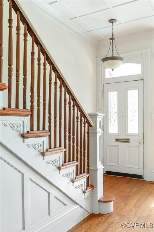 entrance foyer featuring crown molding, coffered ceiling, and light wood-type flooring