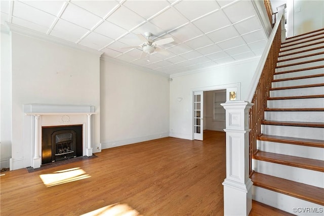 unfurnished living room with wood-type flooring, ornamental molding, and ceiling fan