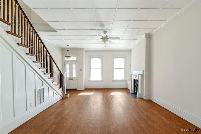 unfurnished living room featuring hardwood / wood-style floors, crown molding, and ceiling fan