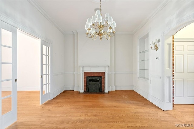 unfurnished living room with hardwood / wood-style flooring, a fireplace, built in features, and crown molding