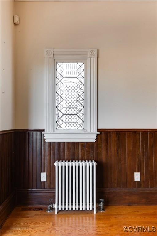 details featuring hardwood / wood-style flooring, radiator, and wooden walls