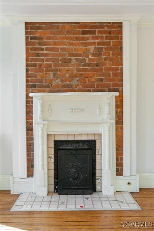 details with a tile fireplace, wood-type flooring, and ornamental molding